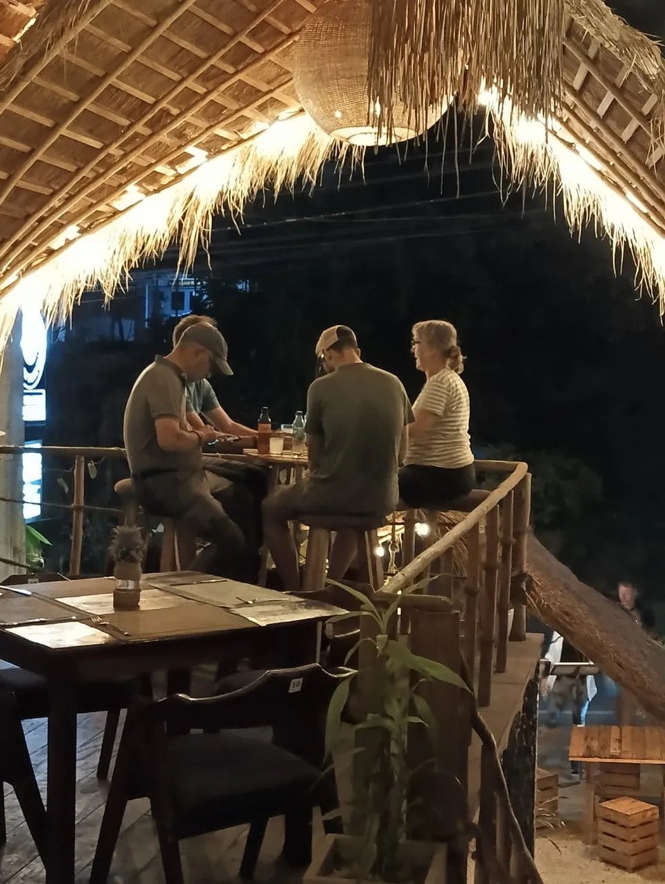 Guests sharing a meal at a high table on the thatched terrace at Chingu Restaurant, Ella